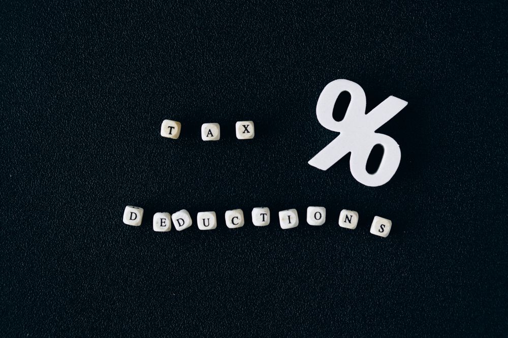 Conceptual image of tax deductions with alphabet blocks and percent symbol on black surface.