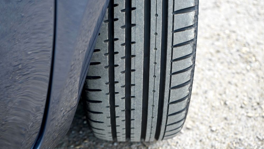 Detailed close-up of a car tire on a gravel road in natural light.