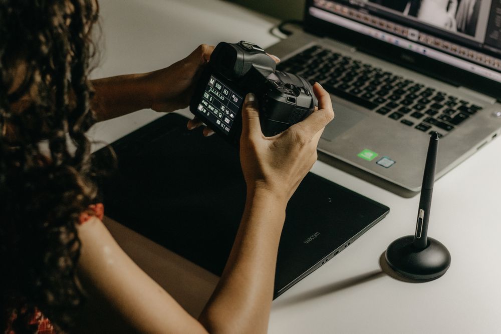 Photographer using a DSLR camera and digital tablet for photo editing on a laptop.