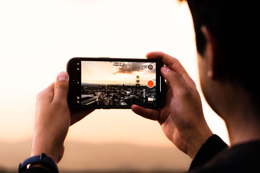 Person filming a city skyline with a smartphone at sunset in Mexico City.