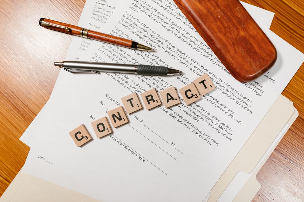 Close-up of contract papers with Scrabble tiles spelling 'CONTRACT'.